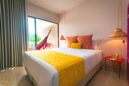 a bedroom with a large bed and a large window at Del Trópico Hotel By GyC Hotels in Sopetrán