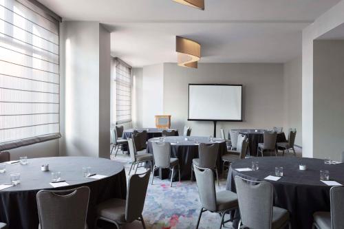a room with tables and chairs and a projection screen at The Lofton Hotel Minneapolis, Tapestry Collection by Hilton in Minneapolis