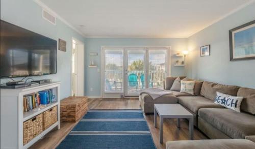 a living room with a couch and a tv at Sea The World- Private Access to Beach in Carolina Beach