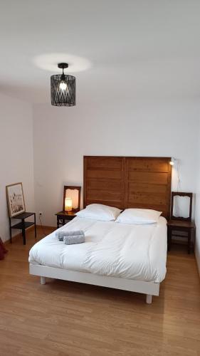 - une chambre avec un grand lit blanc et une tête de lit en bois dans l'établissement Maison de plein pied avec jardin, à Poitiers