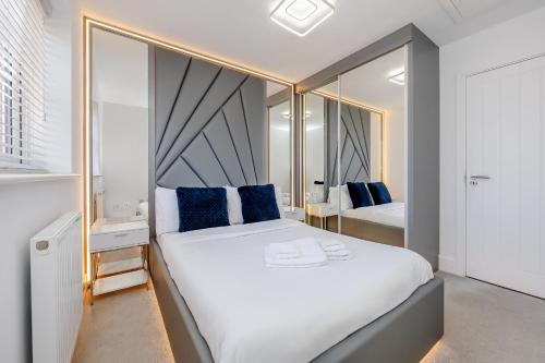 a bedroom with a large white bed with blue pillows at My Chester Luxury Home in Colchester