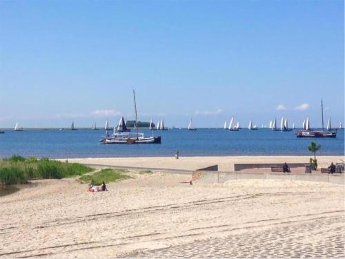 a beach with boats in the water and people on it at Villa by Tjeukemeer with Private Jetty in Delfstrahuizen
