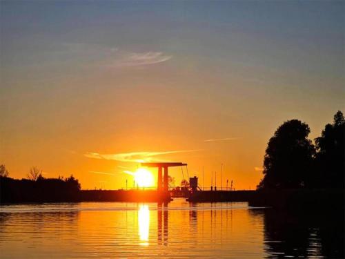 a sunset over a body of water with the sun at Docklodge at Frisian Lakes with Private Mooring in Delfstrahuizen