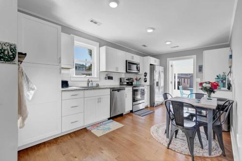 a kitchen with white cabinets and a table with chairs at Turtle Time- Charming 3BR Getaway Near Kure Beach in Kure Beach