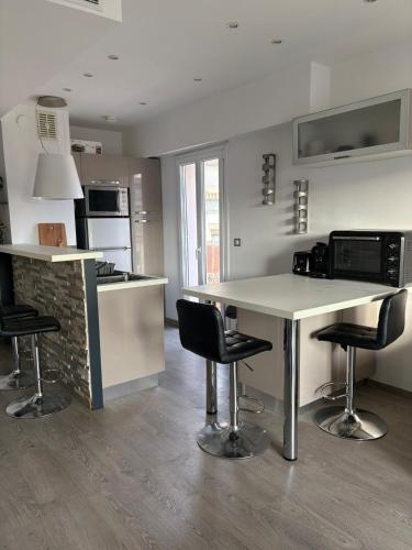 une cuisine avec un comptoir et deux tabourets de bar dans l'établissement Beau studio climatisé très proche de la mer, à Cagnes-sur-Mer