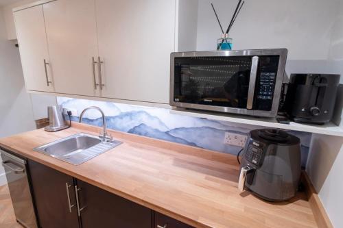 a kitchen with a sink and a microwave at Hidden Home in Haywards Heath