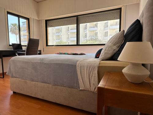 a bedroom with a large bed and two windows at "99 steps to the beach" Beachfront apartment with Kids Room, Pool & 2 Workspaces in Limassol