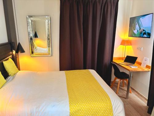 a hotel room with a bed and a desk with a laptop at Appart'hôtel - Seclin-Appartements in Seclin