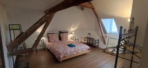 an attic bedroom with a bed and a staircase at Chez Alex' guesthouse in Dozulé
