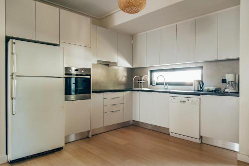 une cuisine avec des armoires blanches et un réfrigérateur dans l'établissement Varkiza Luxury Escape, à Vari