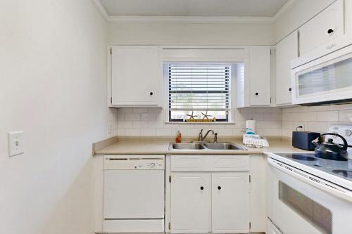 a white kitchen with white cabinets and a sink at Seas the Day in Mallory Park