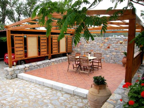 a patio with a table and chairs and a stone wall at Estia Holiday in Gythio