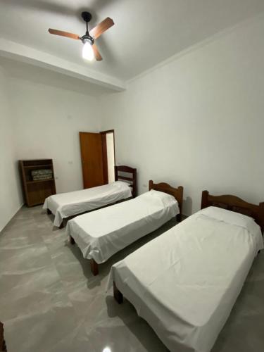 a room with three beds and a ceiling fan at Chácara Namorada do Sol - Pousada e Camping in Guaxupé