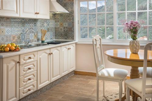 a kitchen with white cabinets and a table with a bowl of fruit at Banana Garden Suites in Hermigua