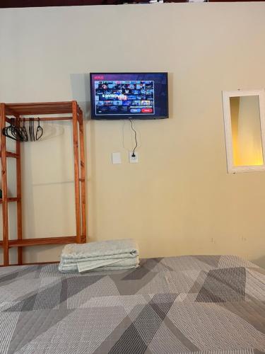 a bedroom with a bed and a tv on the wall at Chalés do vale Extrema azul in Extrema