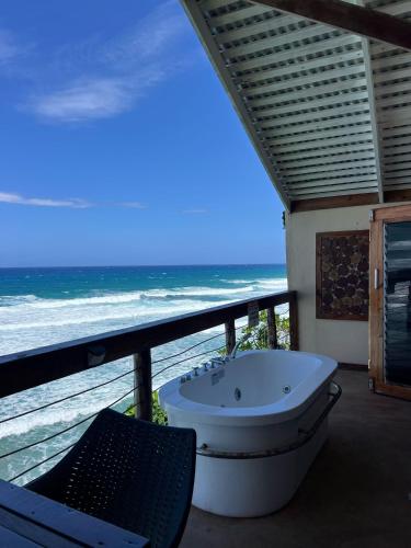 a bath tub sitting on a balcony overlooking the ocean at The Sea Cliff Hotel Resort & Spa in Port Antonio