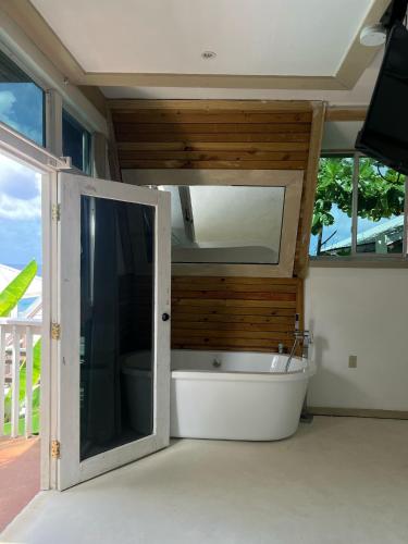 a bathroom with a tub with a mirror and a window at The Sea Cliff Hotel Resort & Spa in Port Antonio