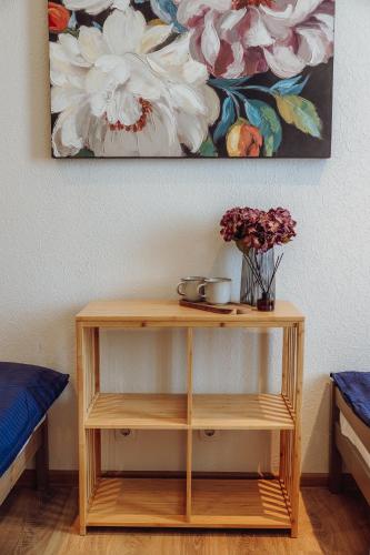 a wooden shelf with flowers and a painting on the wall at Telegrāfs Hotel in Ventspils