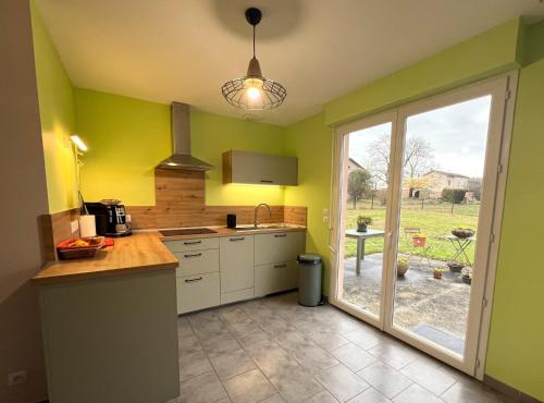 une cuisine avec des murs jaunes et des placards blancs ainsi qu'une fenêtre dans l'établissement Maison au calme proche Albi, à Lescure-dʼAlbigeois