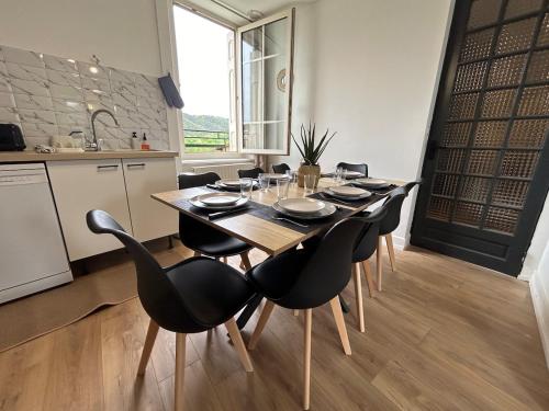 a dining room table with black chairs and a kitchen at Gîte Cosy - 90m2 - T4 - Climatisé - Tout équipé in Retournac