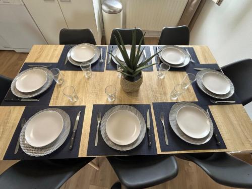 a table with plates and wine glasses on it at Gîte Cosy - 90m2 - T4 - Climatisé - Tout équipé in Retournac