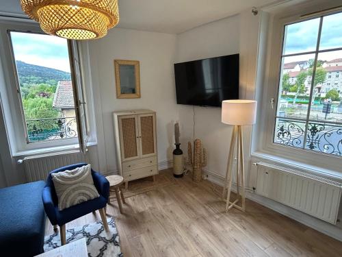 a living room with a tv and two windows at Gîte Cosy - 90m2 - T4 - Climatisé - Tout équipé in Retournac