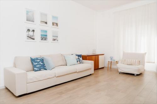 een woonkamer met een witte bank en een stoel bij La Maison Calasetta in Calasetta