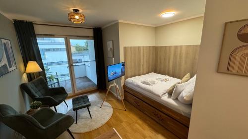 a bedroom with a bed and two chairs and a television at DUHA HOMES - Stylisches Apartment, Stellplatz, Küche, Self Check-in in Ingolstadt