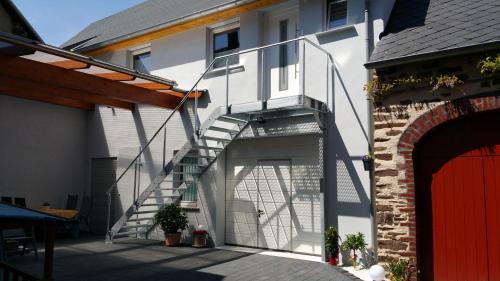 a white house with a garage with a stair case at Ferienwohnung Jo Secco in Bruttig-Fankel