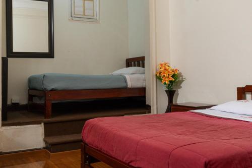 a bedroom with two beds and a vase of flowers at Hospedaje Santa Rosa- Centro Histórico in Lima