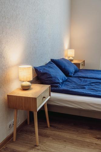 a bedroom with a bed with blue sheets and a nightstand at Telegrāfs Hotel in Ventspils