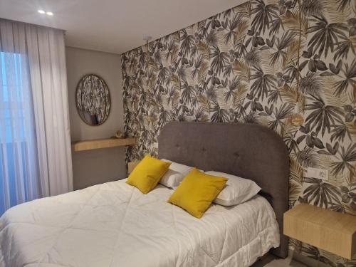a bedroom with a bed with two yellow pillows at Duplex trouville à 2 pas de la plage in 'Aïn el Turk