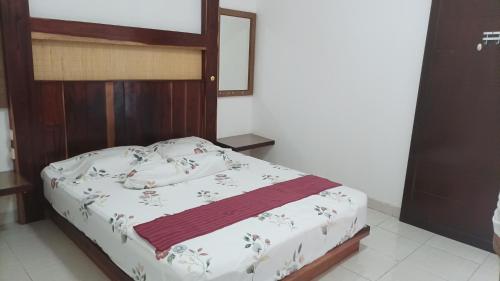 a bed with a wooden headboard in a bedroom at Beruk Angis Guest House & Kost in Palangkaraya