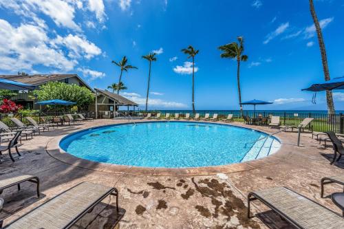 a swimming pool with chairs and the ocean in the background at Kahana Village 31 · KHV 31 Spacious Direct Oceanfront 3BD Condo in Kahana