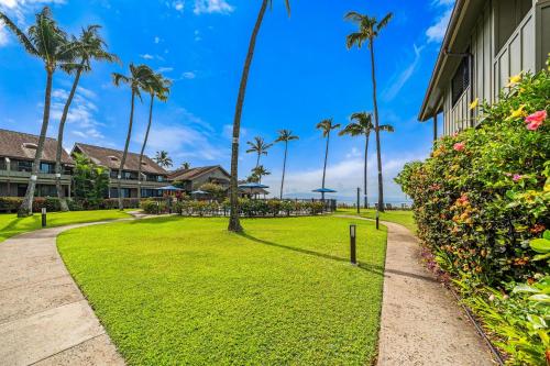 a grassy yard next to a building with palm trees at Kahana Village 31 · KHV 31 Spacious Direct Oceanfront 3BD Condo in Kahana