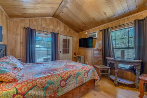 a bedroom with a bed and a desk and windows at Enchanted Hideaway Cabins and Cottages in Ruidoso