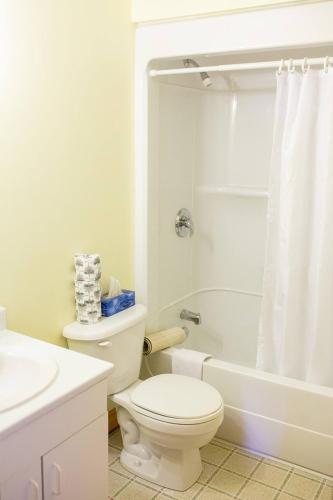 a white bathroom with a toilet and a bath tub at Greenwich View Cottages (Unit #2 - Duplex) in Saint Peters