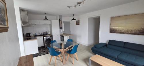 un salon avec un canapé bleu, une table et des chaises dans l'établissement Appartement centre, vue sur Mer, proche Plages, à Douarnenez