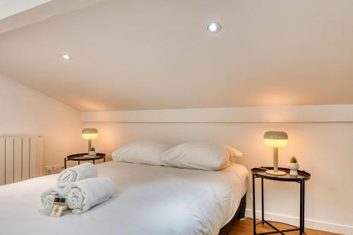 une chambre avec un grand lit blanc avec deux lampes dans l'établissement Le Petit Tolstoï - Appart cosy 2pers, à Villeurbanne