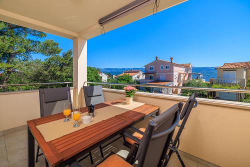 a balcony with a wooden table and chairs with a view at Apartment Iva in Šilo