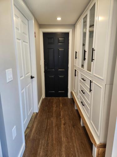 a hallway with a black door and white cabinets at Middletown Modern Townhouse in Middletown