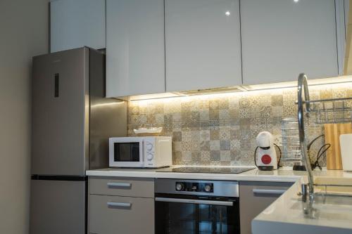 a kitchen with white cabinets and a stove and a microwave at Deluxe Apartments in Gevgelija
