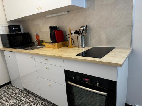 eine Küche mit einer Arbeitsfläche, die mit einem Spülbecken und einem Herd ausgestattet ist in der Unterkunft Apartment in Cergy Prefecture in Cergy