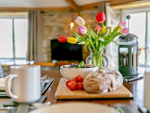 a table with a vase of flowers and a vase of tulips at 1 bed in Tavistock ROUND in Lamerton