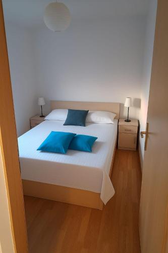 a bedroom with a white bed with blue pillows at Sun and Sea Apartmani Vir Mali in Vir