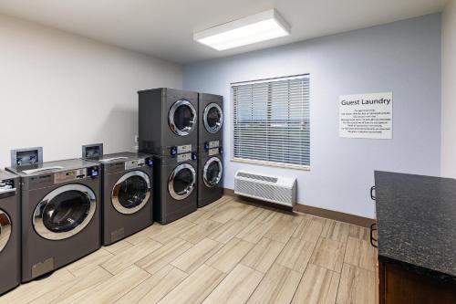 a laundry room with three washing machines and a window at Holiday Inn Express & Suites Tulsa S Broken Arrow Hwy 51 by IHG in Broken Arrow