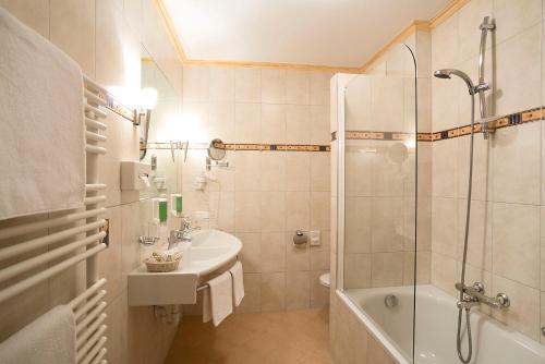 a bathroom with a shower and a sink and a tub at Hotel Auhof in Grossarl