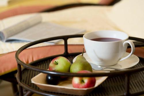 a tray with a cup of coffee and a plate of fruit at Hotel Auhof in Grossarl
