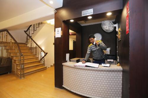 a man standing behind a counter talking on a cell phone at Super Hotel O The Avenue Residency in Gurgaon