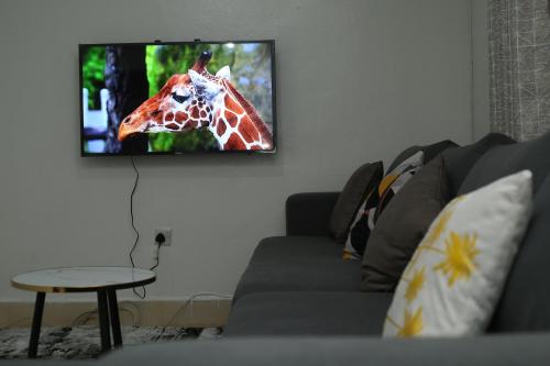 a living room with a giraffe on the tv screen at Cosy 1 bedrooms, Hells Gate Moi South Lake Naivasha in Naivasha